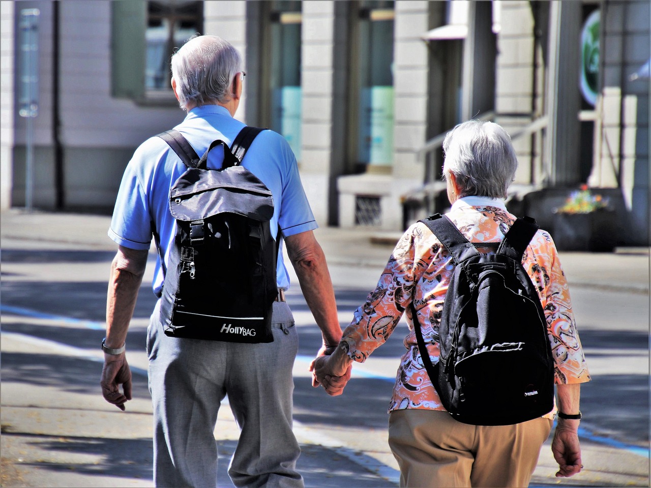 An older couple walking down a city street holding hands